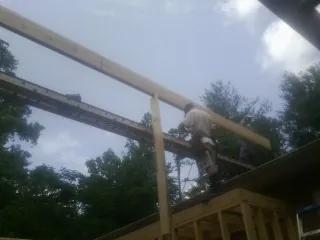 Carpenter setting a ridge beam over a new addition frame — Ice Dam Removal by Roofing Brothers in Wasco