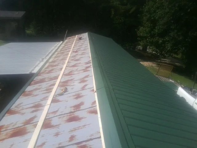 Old rusted panels beside newly installed green metal roofing — Wind Damage Roof Repair by Roofing Brothers in Wasco